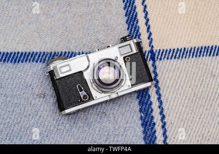 Film camera on a plaid on white boards. Stock Photo