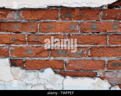 Decaying of erosion mossy red brick wall with remains of plaster of 18th century building Stock Photo