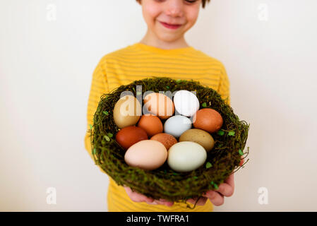 Portrait of a smiling boy holding a nest with fresh eggs Stock Photo