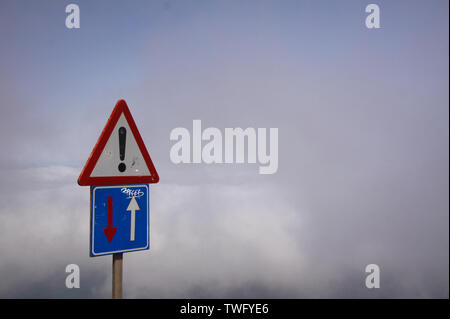 Mirador del Rio - Lanzarote:  Isolated warning sign für one way traffic above clouds (Focus on left sign) Stock Photo