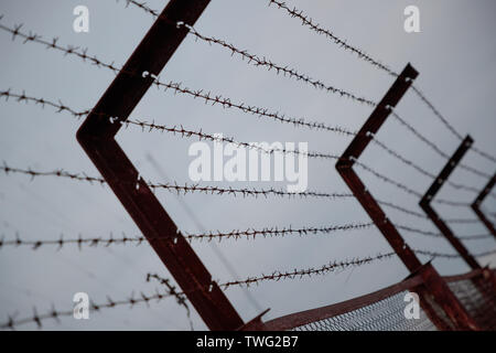 barbed wire on the fence in cloudy weather Stock Photo