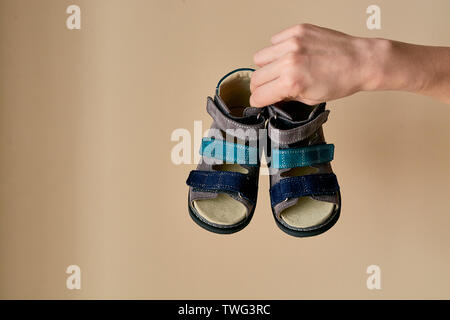 Female is holding close-up a special children's orthopedic shoe sandals made of genuine leather. Comfortable shoes isolated on light background with c Stock Photo