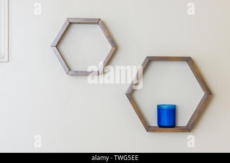 Hexagon shaped floating shelves with blue candle and empty space Stock Photo