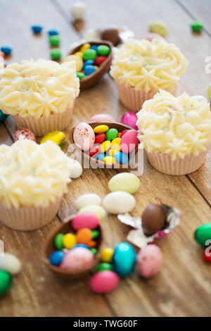 cupcakes with chocolate eggs and candies on table Stock Photo