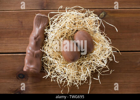 chocolate bunny and eggs in straw nest on wood Stock Photo