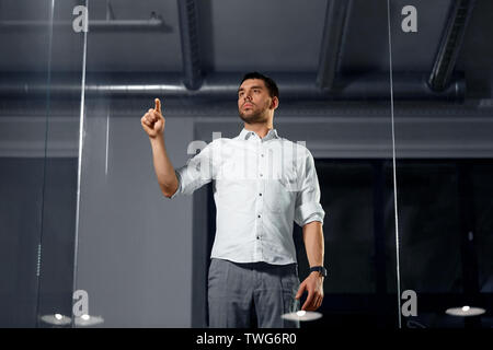 businessman touching glass wall at night office Stock Photo