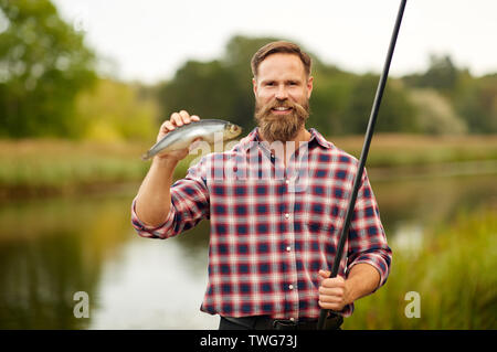 Caucasian adult bearded men stand near lake and hold fishing rod. Here he  with his son, he shows how hold fishing rod correctly Stock Photo - Alamy