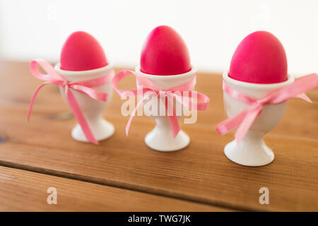 three pink colored easter eggs in holders on table Stock Photo