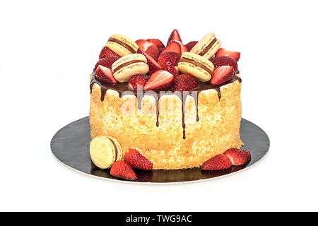 Triple vanilla cream cake chocolate frosted with macaroons and ripe strawberries on top Isolated on white background Stock Photo