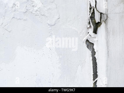 Large crack on the white concrete wall of the urban house. Stock Photo