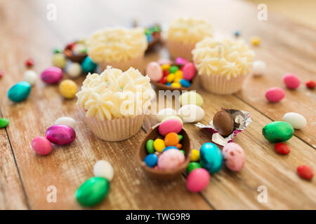 cupcakes with chocolate eggs and candies on table Stock Photo