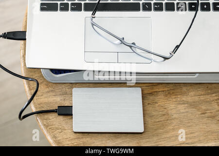 Notebook grey modern black keyboard with hdd grey and spectacles on wood table Stock Photo