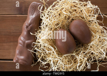 chocolate bunny and eggs in straw nest on wood Stock Photo