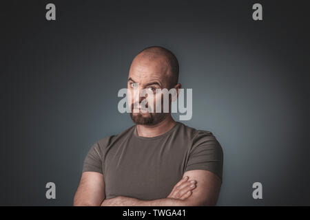 studio portrait of man with doubtful expression and arms crossed, casual clothes Stock Photo