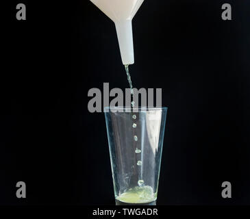 Apple juice drops from a white funnel into a glass cup Stock Photo