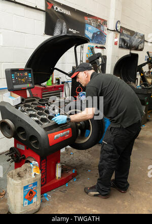 Mechanic balancing car wheels after new tyre was fitted. Bury Tyre Centre in Bury St Edmunds, Suffolk, UK Stock Photo