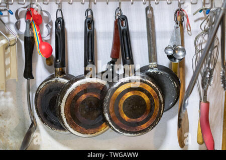 Kitchenware pan and spoon hanging on rack in kitchen Stock Photo
