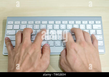 Hand professional programmer typewriting on modern white keyboard on wooden desk Stock Photo