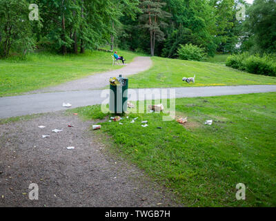 Helsinki, Finland- June 11, 2019: Waste next to trash bin in a park in Helsinki, Finalnd Stock Photo
