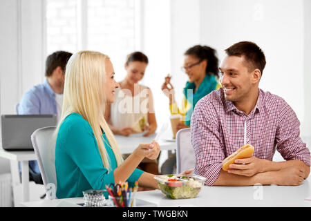 happy colleagues having lunch and eating at office Stock Photo