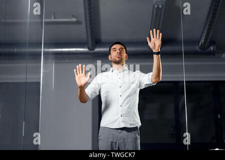 businessman touching glass wall at night office Stock Photo