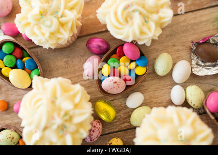 cupcakes with chocolate eggs and candies on table Stock Photo
