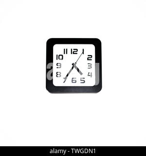 Wall clock - square black wall clock on a white wall Stock Photo