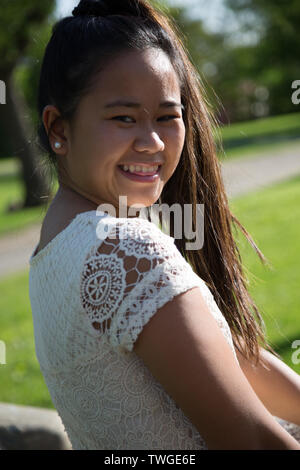 A beautiful teenage girl with a long pony tail poses for the camera. Stock Photo