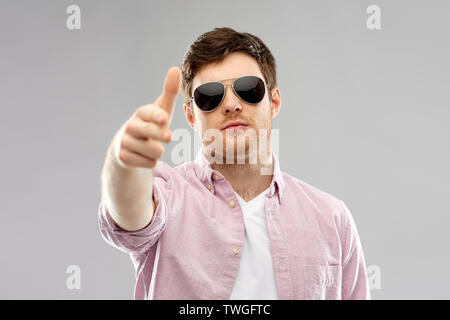 young man in sunglasses making hand gun gesture Stock Photo