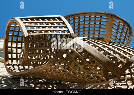 Cambridge Uk, 2019-05-22, close up Twisted wooden artwork on side of University building casting shaow in miday sunshine Stock Photo