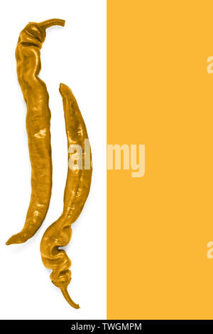 Two pods of chili peppers golden colored on a white and orange background Stock Photo