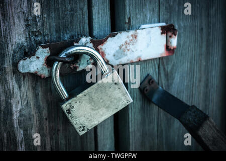Hanging castle on the doors of an abandoned old barn in the style of post-apocalypse Stock Photo