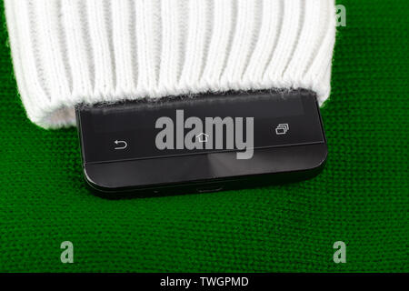 cellphone sticking out from knitted fabric like sweater or mittens. Stock Photo