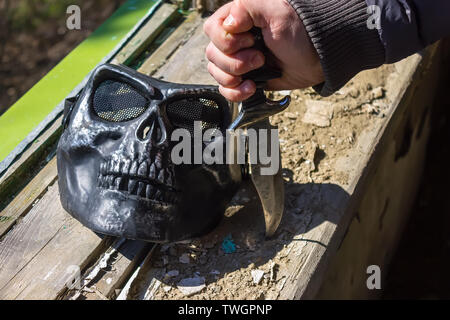 Knife in hand and mask near the destroyed window Stock Photo