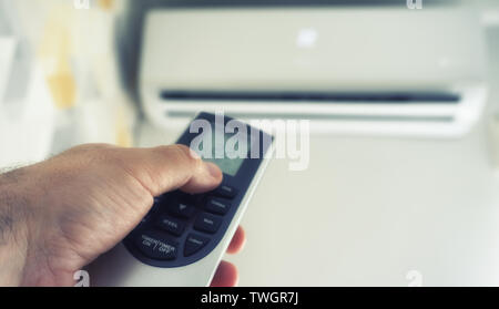 Hand hold remote control directed on the air conditioner Stock Photo