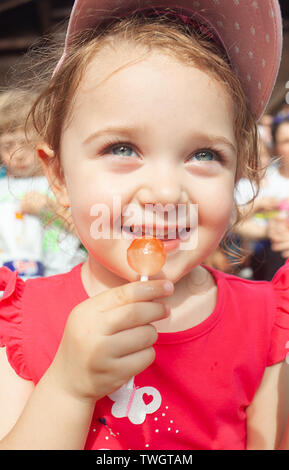 Cute little girl holding in hand a cherry lollipop. Stock Photo