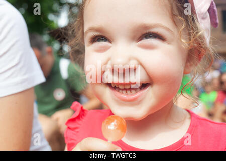 Cute little girl holding in hand a cherry lollipop. Stock Photo