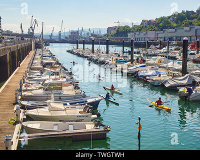 Kids kayaking in the Muelle del Hospitalillo harbour of Trintxerpe, on a sunny day. Pasaia, Gipuzkoa, Basque country, Spain. Stock Photo
