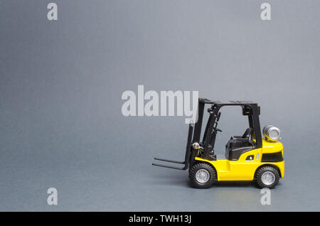 Yellow forklift truck side view on gray background. Warehouse equipment, vehicle. Unloading, transportation, sorting, loading cargo. Logistics and tra Stock Photo