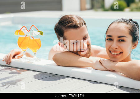 happy heterosexual couple is well rested with cocktails while in the pool. Summer rest Stock Photo