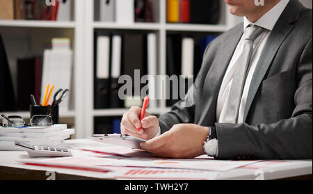Businessman working and calculating, reads and writes reports. Office employee, table closeup. Business financial accounting concept. Stock Photo