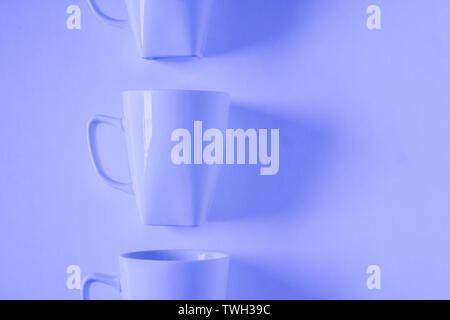 One singled out monochromatic blue coffee mug lined up in a row on blue background with blank empty room space for text, copy, or copyspace. Modern to Stock Photo