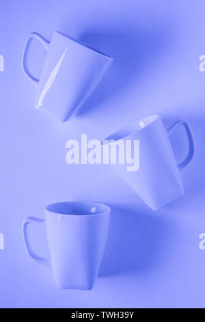 3 monochromatic blue coffee mugs scattered on blue background with blank empty room space for text, copy, or copyspace. Modern top view concept of thr Stock Photo