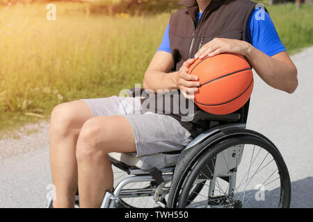 Disabled young basketball player on a wheelchair holding ball and beeing active in sport Stock Photo