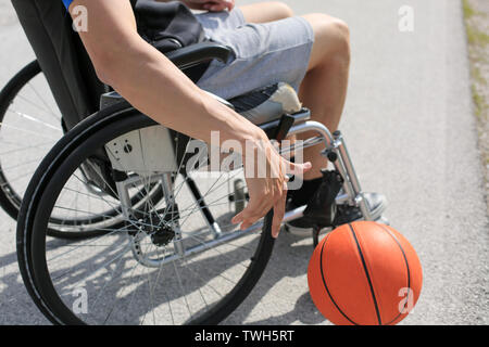 Disabled young basketball player on a wheelchair holding ball and beeing active in sport Stock Photo