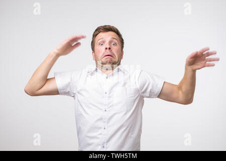 Young european man waving his hands around in fear on gray background Stock Photo