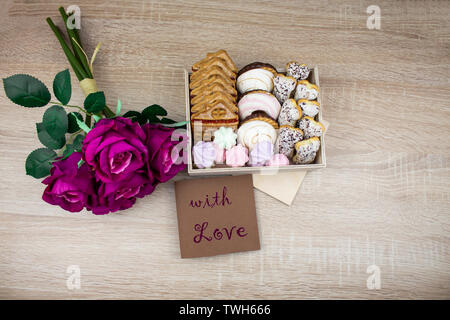 Chocolate cookies on a wooden table. A variety of cookies in a box with flowers and a card. Assorted cookies. copy space Stock Photo