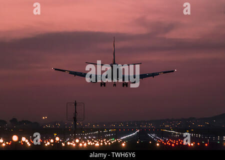 Passenger aircraft landing at the Cape Town International Airport at dusk with the landing strip clearly lit up.