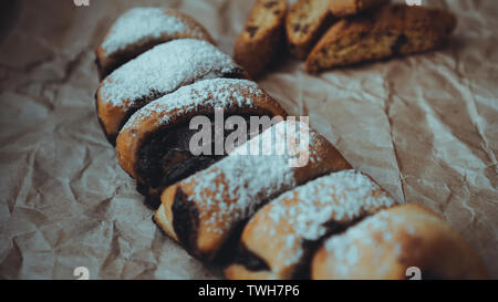 Freshly Baked Chocolate Rolls with a delicious filling, sprinkled with powdered sugar. Against the background of brown craft paper Stock Photo