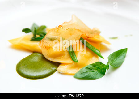 Ravioli with pesto sauce and potato chips, close-up Stock Photo